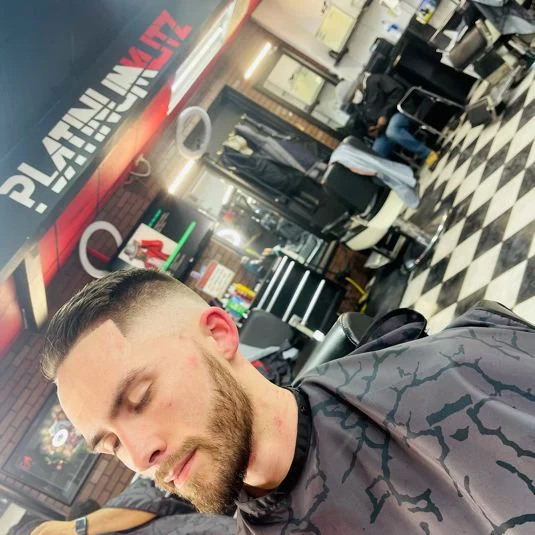 Close-cropped haircut and shaped beard by Tyler