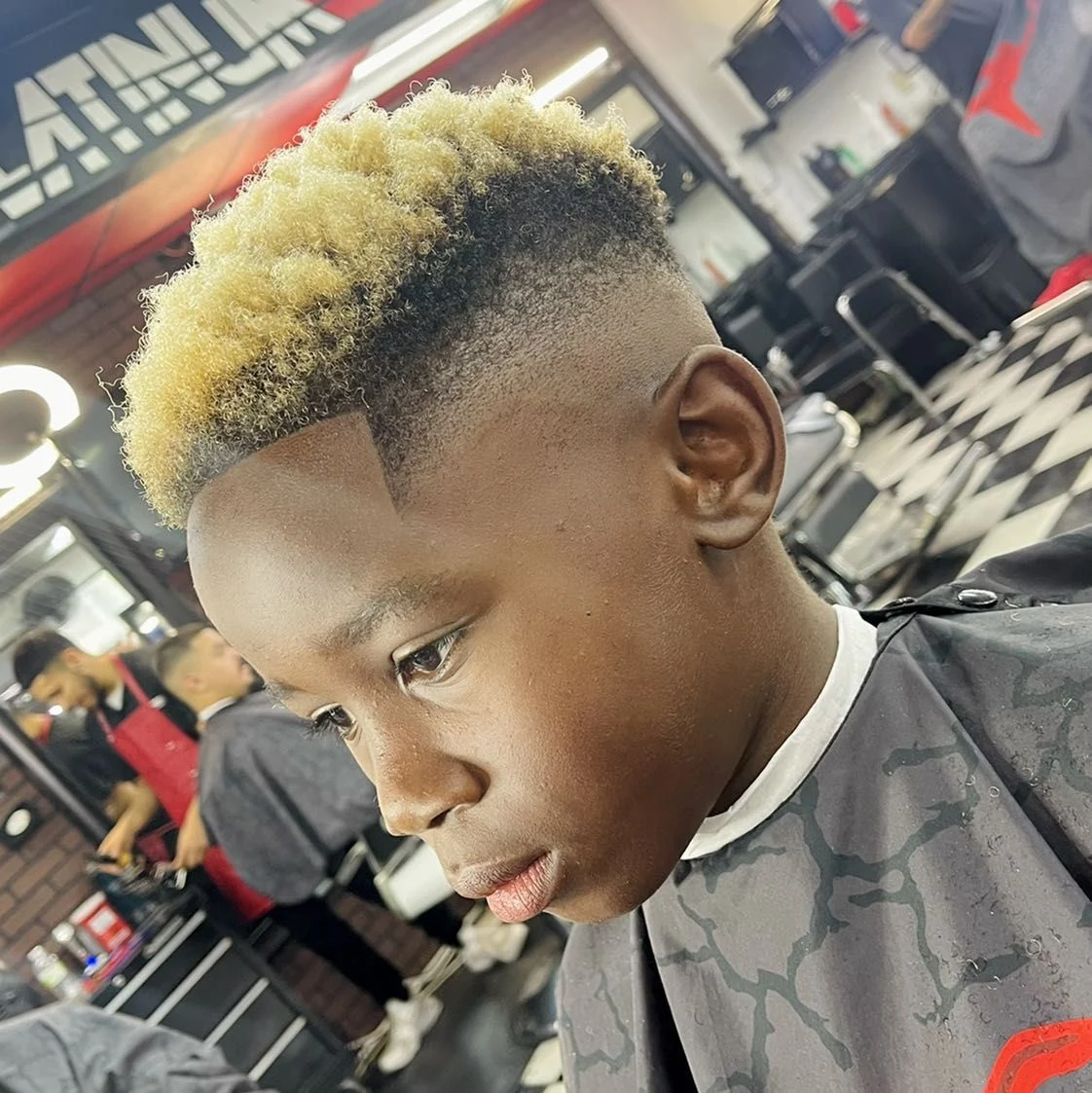 Blond textured curls with closely faded sides and a precise hairline by Tyler